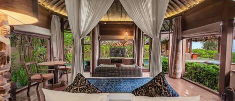 A room with a bed, a TV, and a view of a garden.