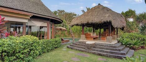 Un resort tropical con estructuras de techo de paja, piscina y exuberante follaje.