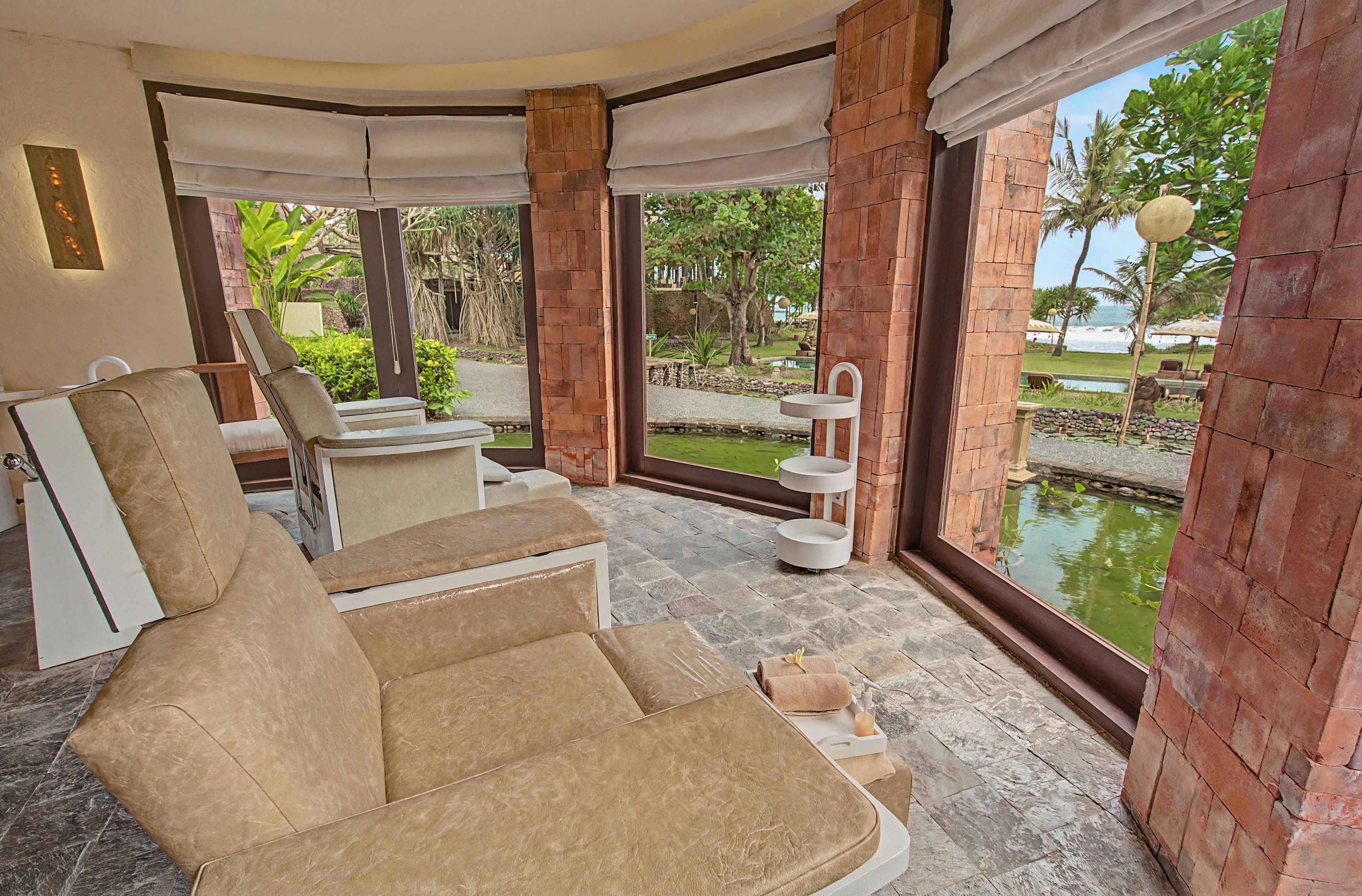 A room with a large window, a chair, a small table, and a water feature.