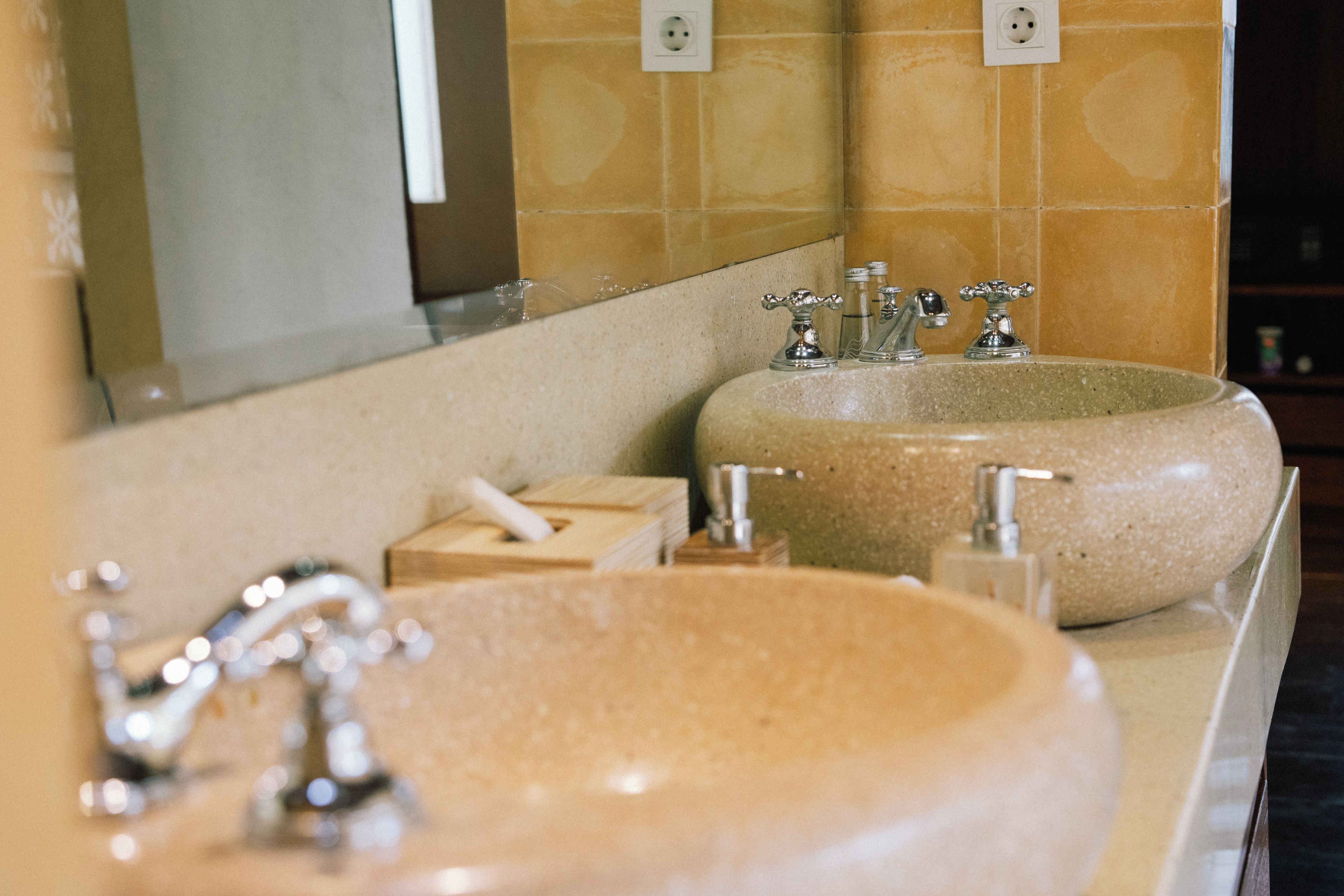 A bathroom with two sinks, a mirror, and a towel dispenser.