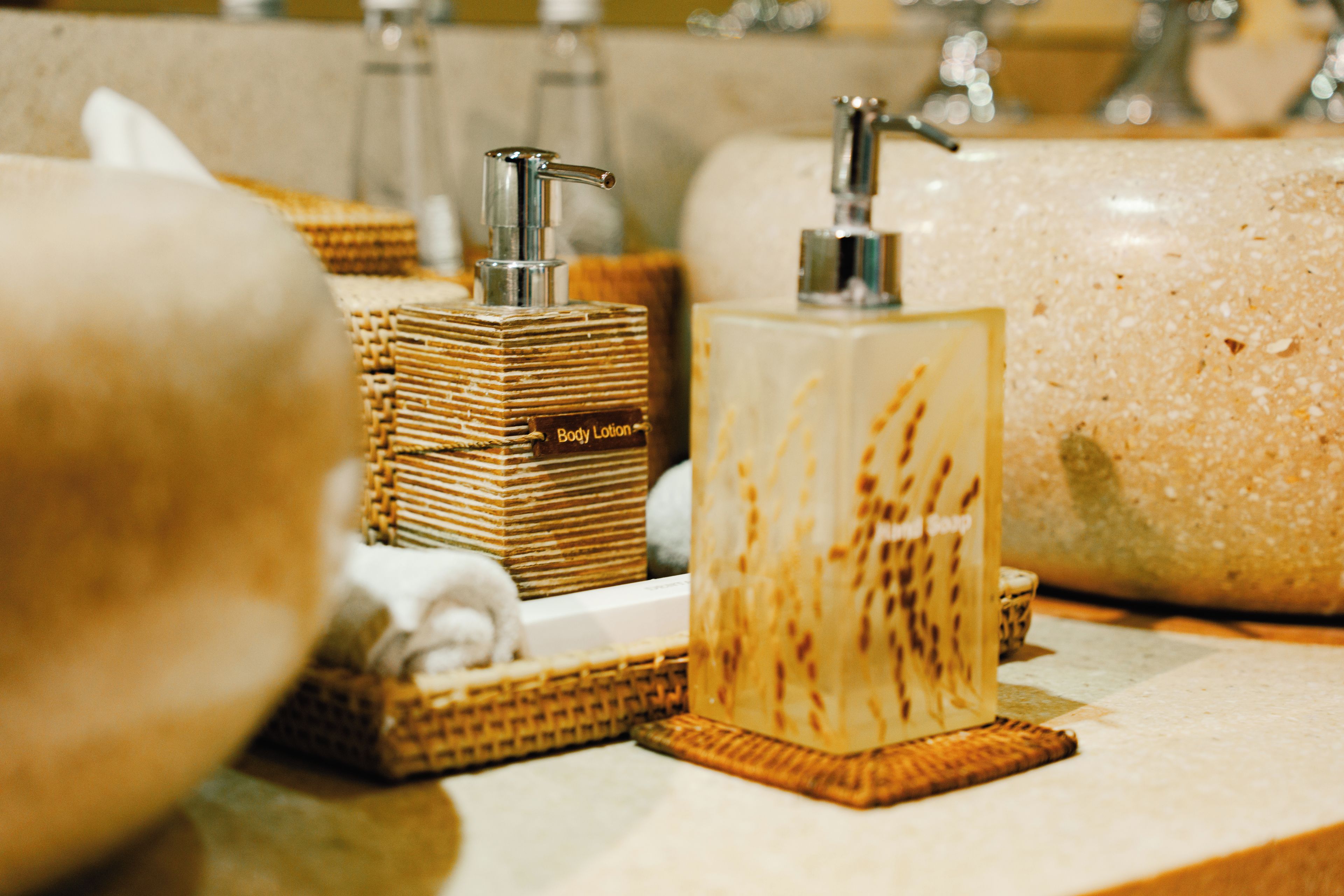 A bathroom vanity with a soap dispenser, a bottle of body lotion, and a towel.