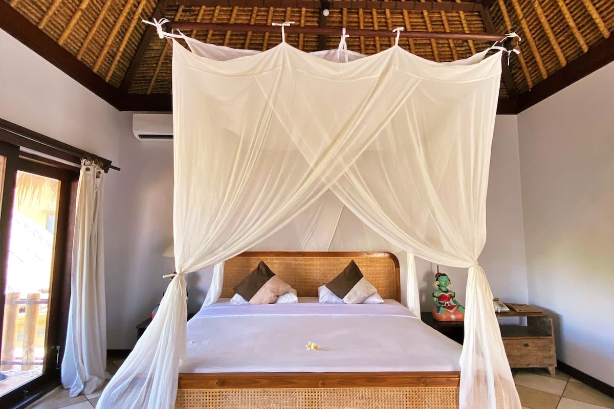 A bed with a canopy, wooden headboard, and pillows.