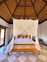 A bed with a canopy, wooden headboard, and pillows.