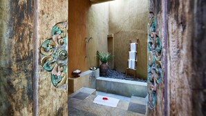 A bathroom with a bathtub, a shower, and a sink. There is a towel rack and a plant. - Visakha Sanur by Puri Signatures (Denpasar)