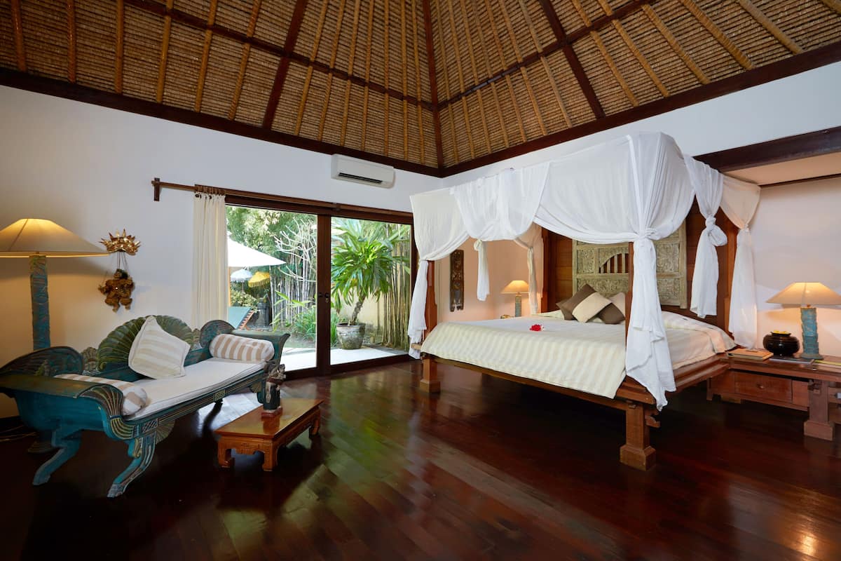 A spacious room with a large bed, a sofa, and a dining table.