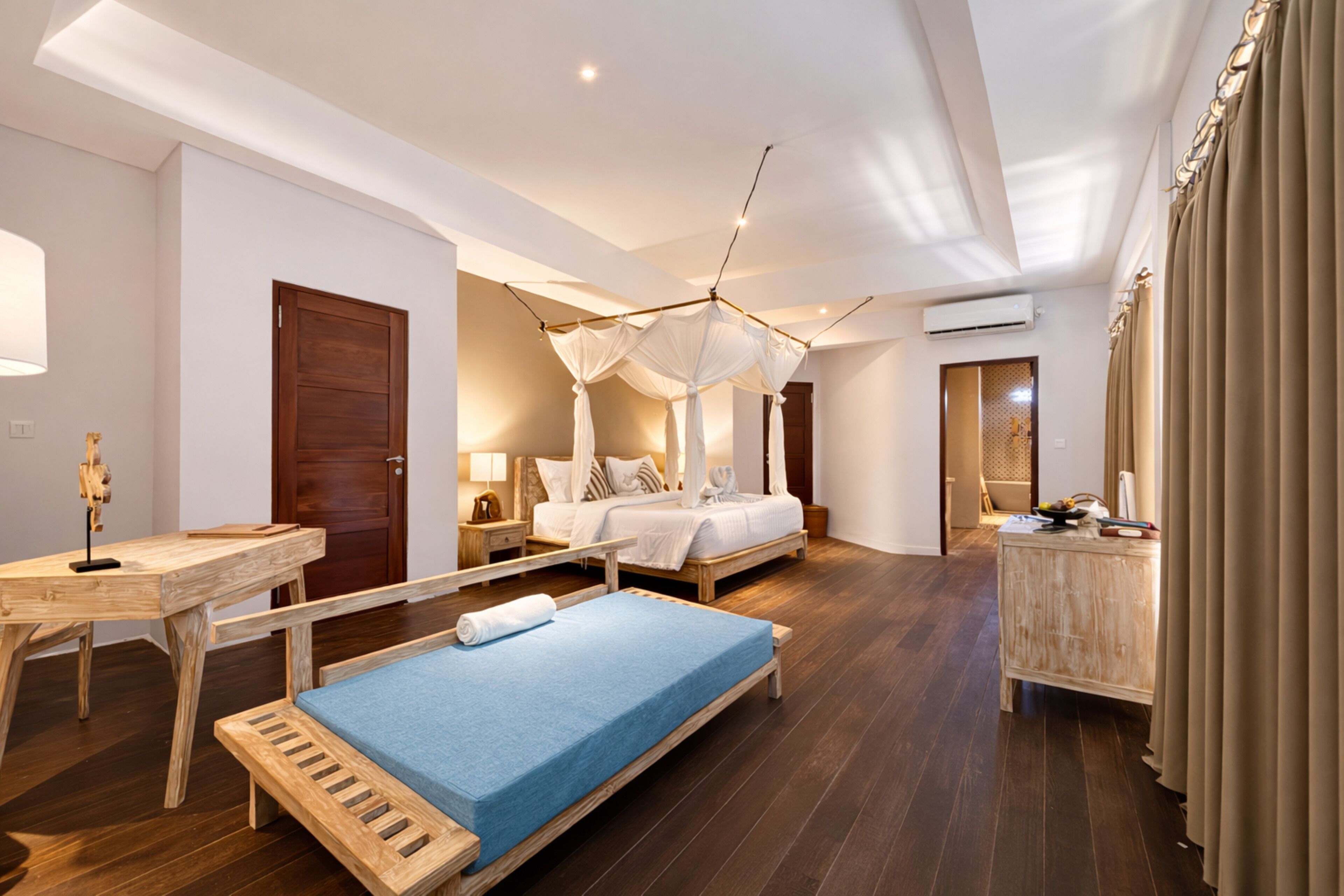 Une chambre à coucher avec un lit à baldaquin, une banquette, un bureau en bois et une commode.