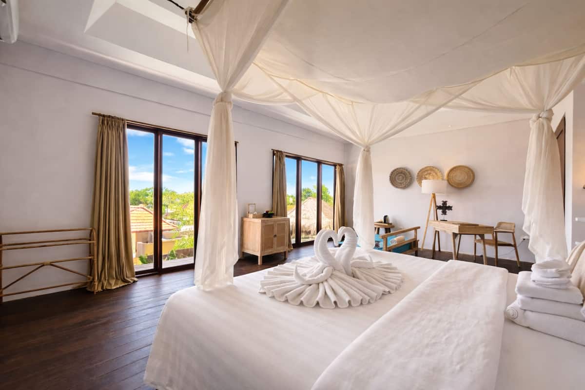 A hotel room with a large bed, a desk, and a view of the outdoors.