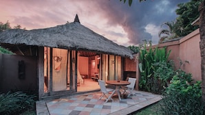 A thatched-roof structure with a checkered patio, white chairs, and a table. - Visakha Sanur by Puri Signatures (Denpasar)