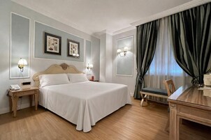 Una camera d'albergo con un letto grande, comodini, una scrivania e una sedia.