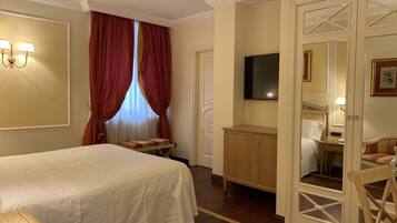 Una habitación de hotel con cama, escritorio, televisor y espejo.