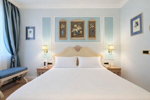A hotel room with a large bed, two bedside tables, a chair, and wall-mounted lamps.
