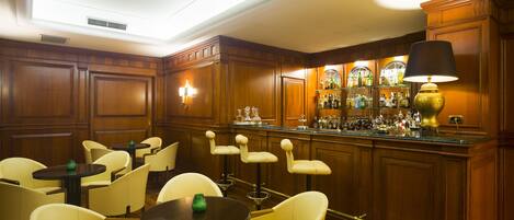 Zona de bar con paneles de madera, taburetes y una amplia selección de licores.