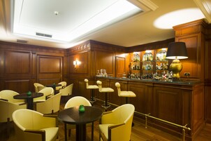 Angolo bar con rivestimenti in legno, sgabelli da bar e ampia selezione di liquori.