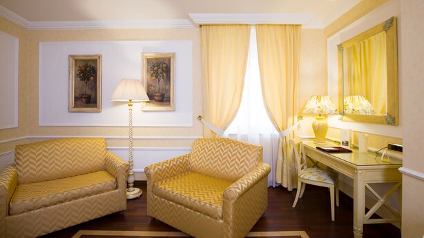 Una habitación con dos sillones, un escritorio, una lámpara y dos cuadros en la pared.