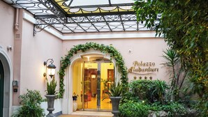 Entrada de un hotel con un balcón de hierro forjado, una puerta de vidrio y un letrero que dice "Palazzo Alabardieri".