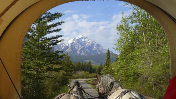 A view through a window with a mountain in the background. - Red Carpet Inn (Banff)