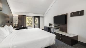 Una habitación de hotel con una cama grande, un escritorio con televisión de pantalla plana y una ventana con cortinas.