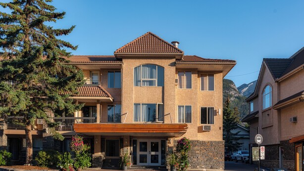 A multi-story building with a stone facade, large windows, and a covered entrance area.