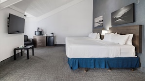 Habitación de hotel con una cama grande, un escritorio, una cafetera y un televisor de pantalla plana.