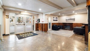 A hotel lobby with a reception desk, seating area, and a fireplace.