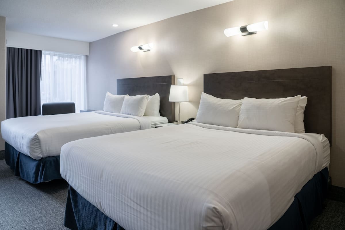 Habitación de hotel con dos camas tamaño queen, un escritorio y una silla.