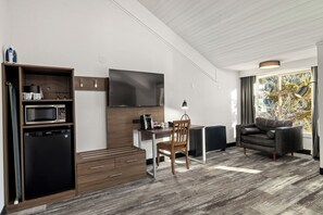 Un espacio habitable compacto con kitchenette, televisor de pantalla plana, comedor y zona de estar con vistas al exterior.