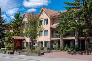 A multi-story hotel with a stone facade, balconies, and a Red Carpet Inn sign. - Red Carpet Inn (Banff)