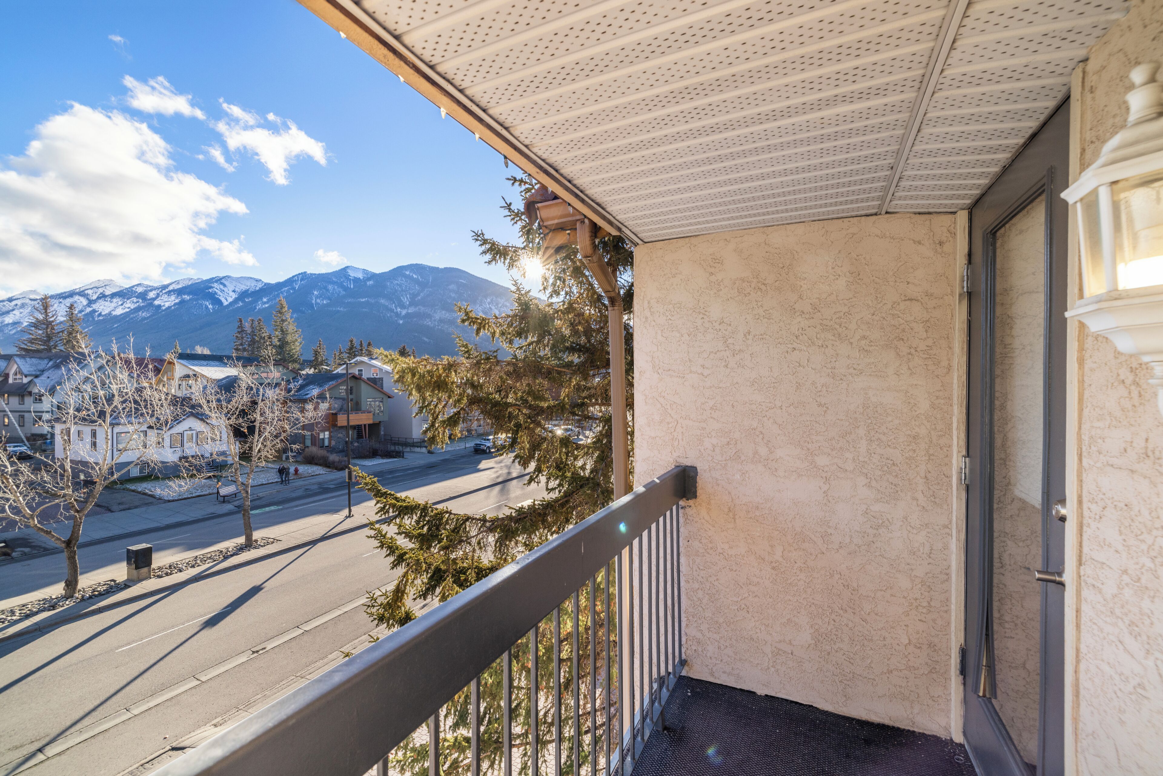 Un balcon donnant sur une rue, des immeubles et des montagnes.