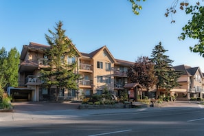 A multi-story hotel with balconies, a parking area, and a clear sky. - Red Carpet Inn (Banff)