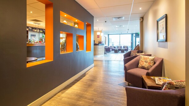 Un hall d’hôtel comprenant un comptoir d’accueil, un espace salon et un bar.