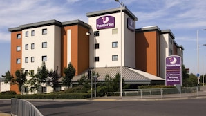 Un hôtel Premier Inn au design moderne, avec une enseigne bien visible, plusieurs étages et un espace de stationnement.