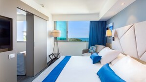 A modern hotel room with a large bed, a TV, a desk, and a view of the sea. - Valamar Diamant Hotel (Porec)