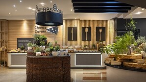 A modern restaurant interior with a central counter, wooden accents, and a variety of plants. - Valamar Diamant Hotel (Porec)