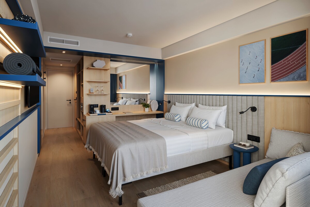 A modern hotel room with a large bed, bedside tables, a desk, and a seating area.