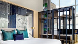 Quarto de hotel moderno com uma cama grande, vista da cidade e um design de teto único.