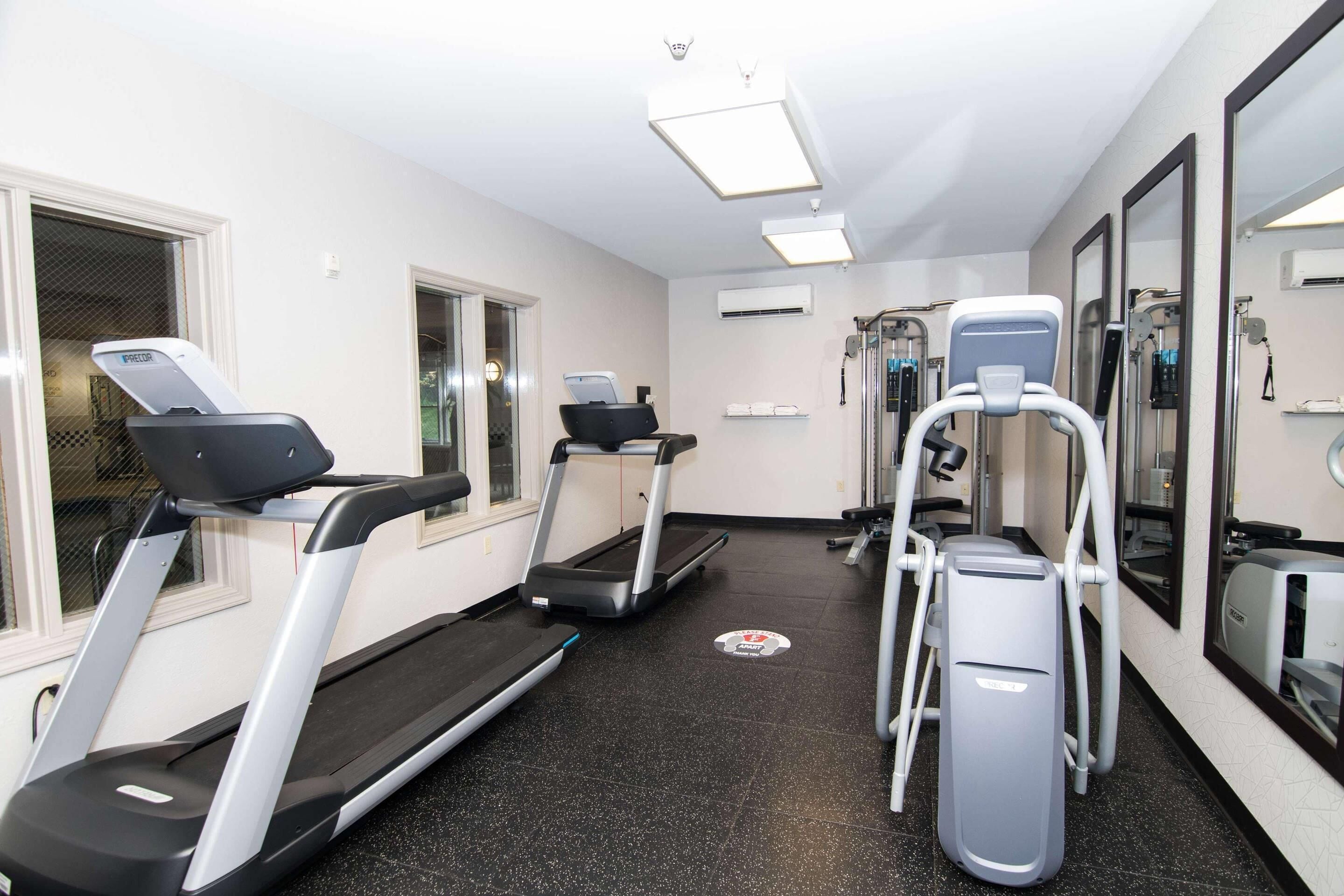 A fitness room with treadmills, a stair climber, and a weight machine.
