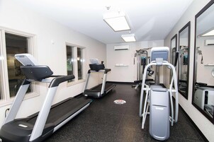 Gimnasio con cintas de correr, escaladora y máquina de pesas.