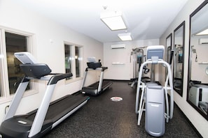 A fitness room with treadmills, a stair climber, and a weight machine.