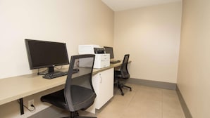 A clean, modern office space with a desk, two monitors, a printer, and a black office chair.