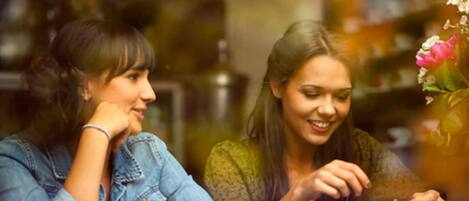 Dos personas sentadas a una mesa con tazas, probablemente en un café o restaurante.