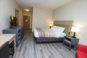 A hotel room with a bed, bedside tables, a desk, a chair, and a television.