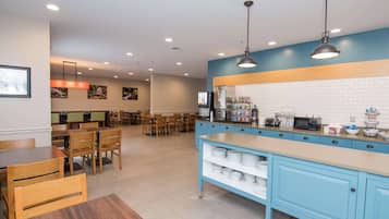 Un café moderno con una barra alargada, zona de estar y cocina equipada.
