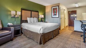 Una habitación de hotel con una cama, un escritorio, una silla y una mesita de noche.
