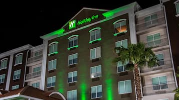 Hotel de diversos pisos amb un senyal prominent de 'Holiday Inn', balcons i una palmera.