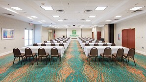 A conference room with multiple tables and chairs, a carpeted floor, and a Holiday Inn sign on the wall. - Holiday Inn & Suites Lake City by IHG (Lake City)