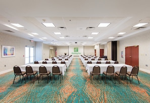 A conference room with multiple tables and chairs, a carpeted floor, and a Holiday Inn sign on the wall. - Holiday Inn & Suites Lake City by IHG (Lake City)