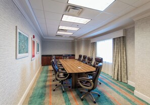 A conference room with a long table and chairs, a carpeted floor, and a window with curtains. - Holiday Inn & Suites Lake City by IHG (Lake City)