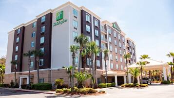 A Holiday Inn hotel with multiple floors, a parking lot, and palm trees.