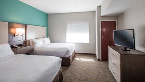 Een hotelkamer met twee bedden, een televisie, een bureau met lamp en een raam met zonwering.