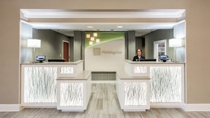 A reception desk with a Holiday Inn sign, two computer monitors, and a security camera. - Holiday Inn & Suites Lake City by IHG (Lake City)